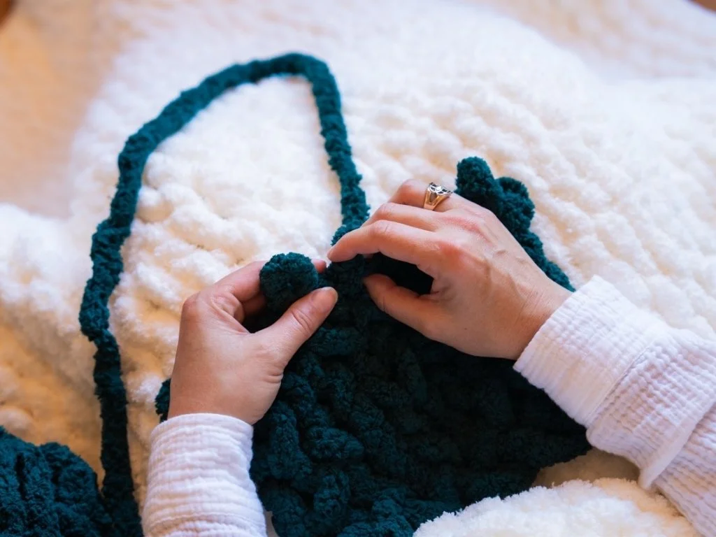 Close up of hands finger-knitting a blanket with chunky yarn