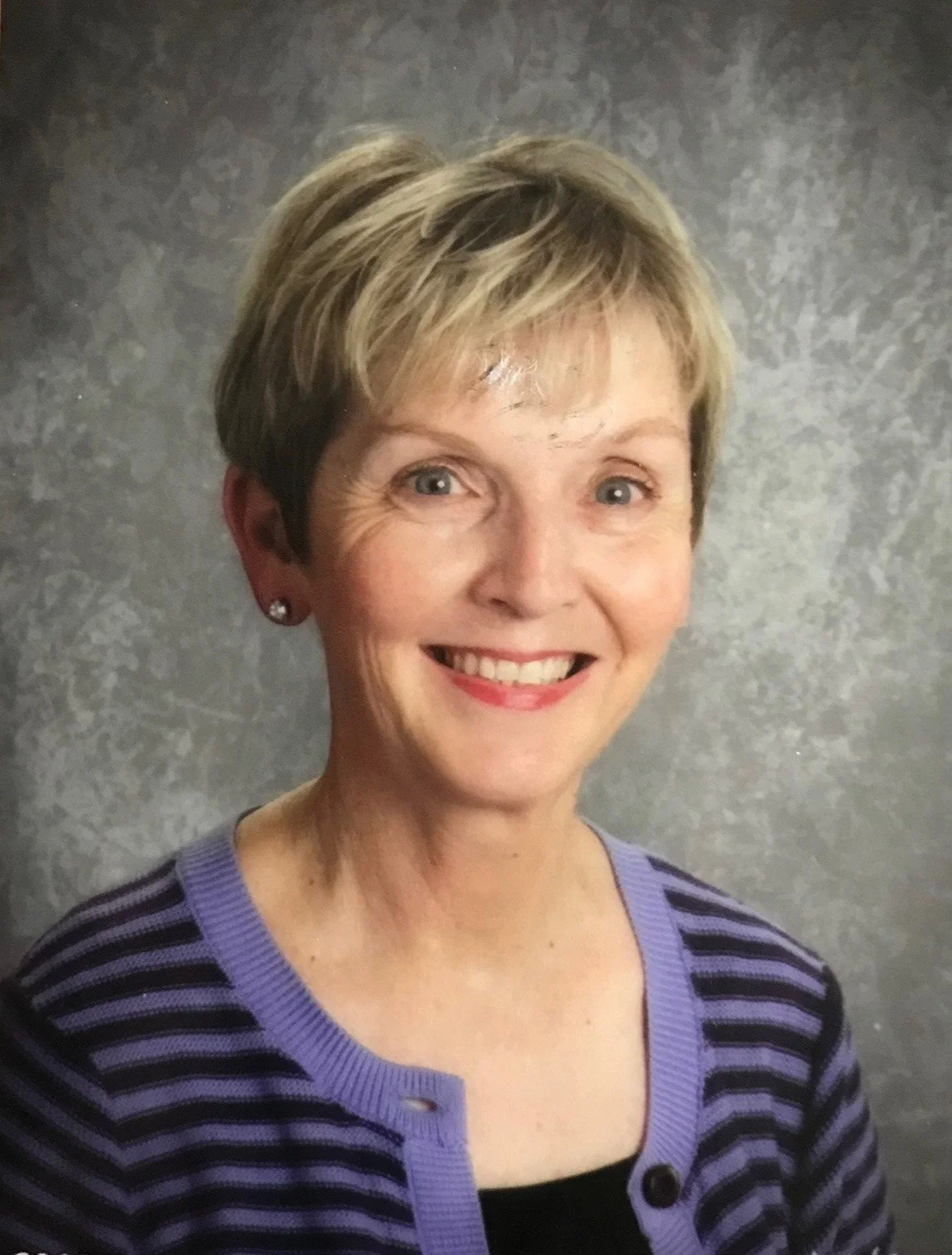 Headshot of Miss Kathy in a purple and black striped sweater