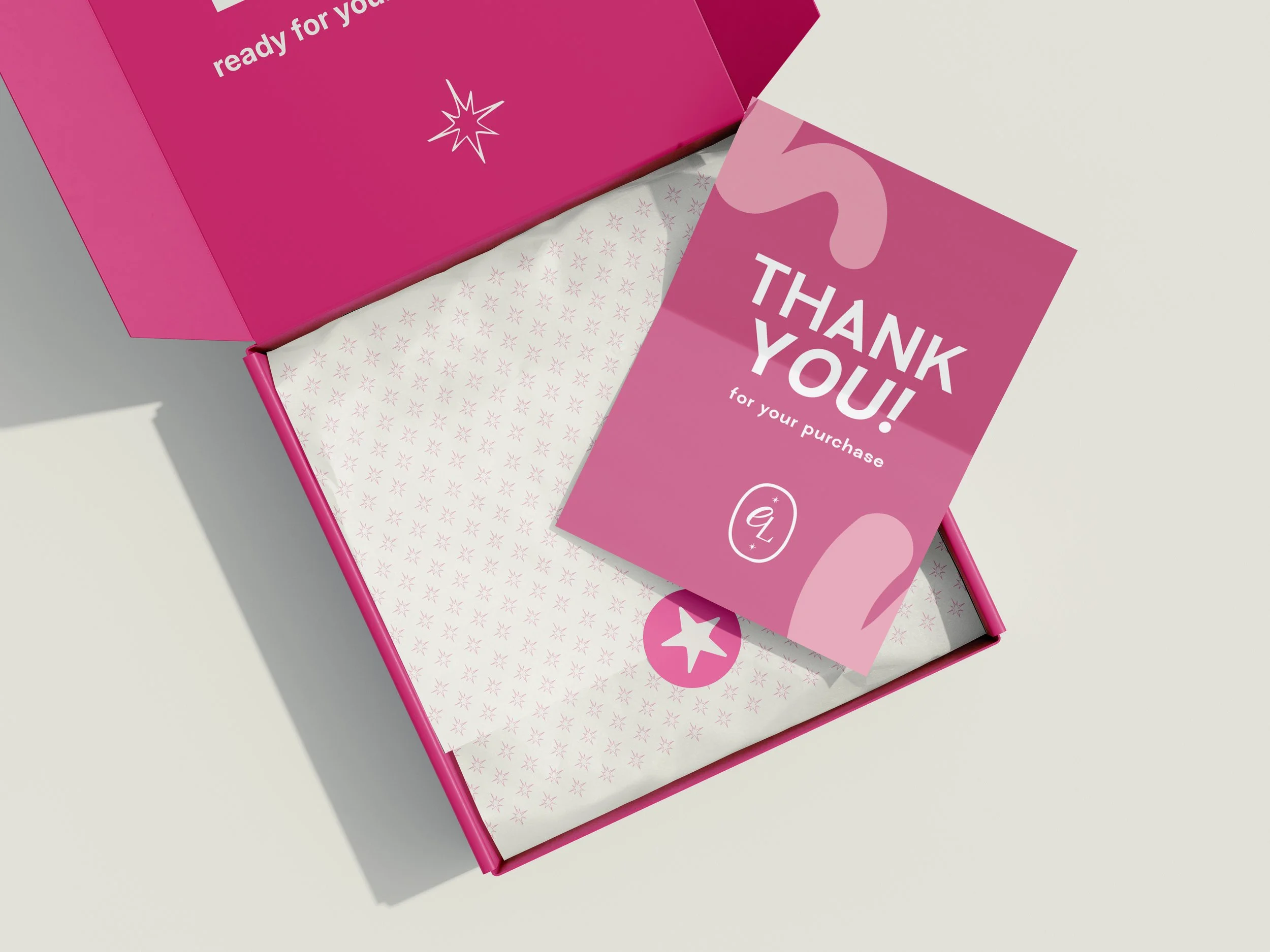 Caja rosa con papel decorativo y una tarjeta que dice 'Thank you! for your purchase' sobre una superficie blanca.
