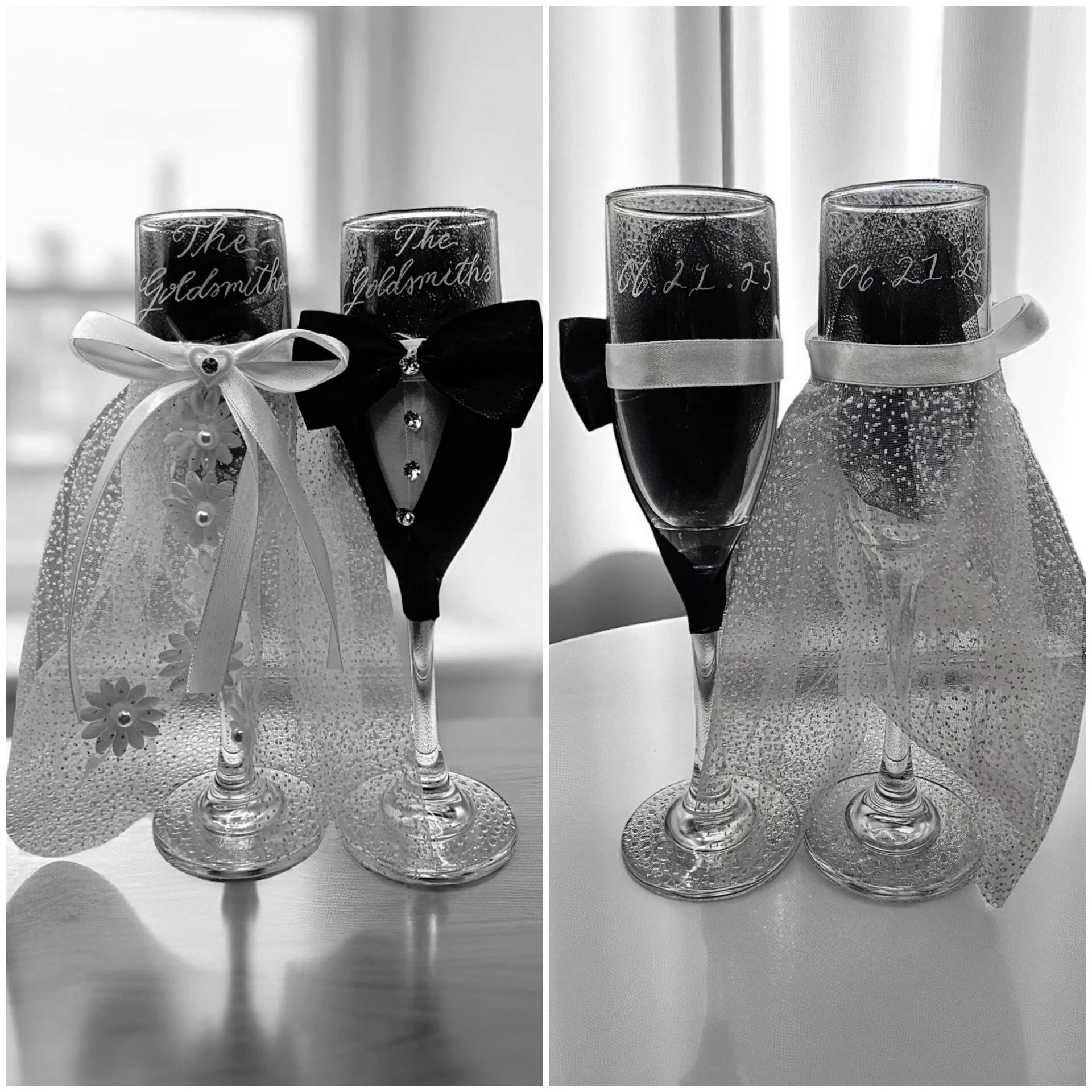 Two champagne glasses decorated as wedding-related theme, with lace and ribbons, on a table. One glass has a white ribbon with a heart-shaped gem, the other has a black ribbon with rhinestones. There are two matching glasses with water droplets, ribb