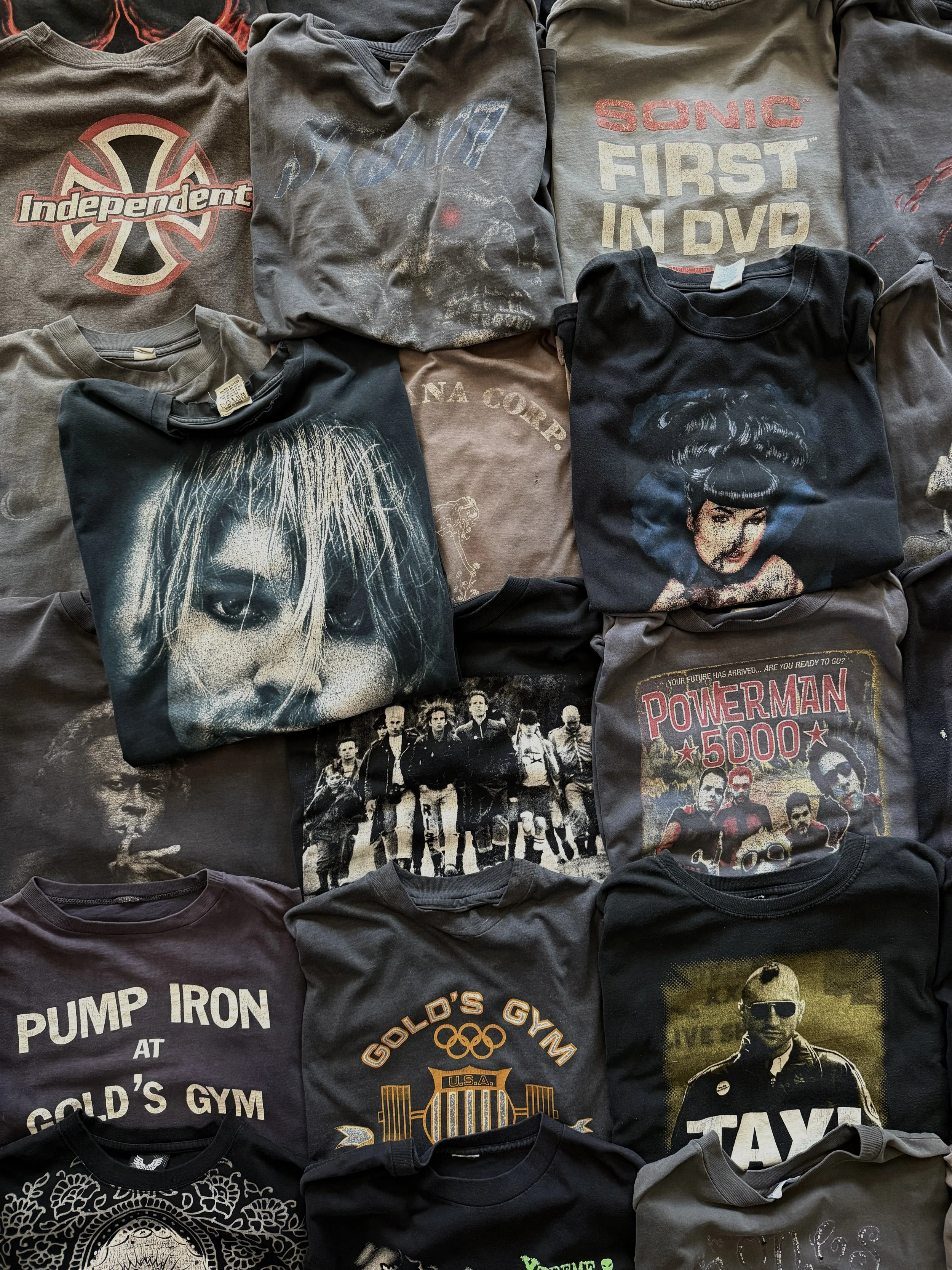 Collection of various T-shirts with different graphic designs and logos, including music bands, movies, and pop culture references.