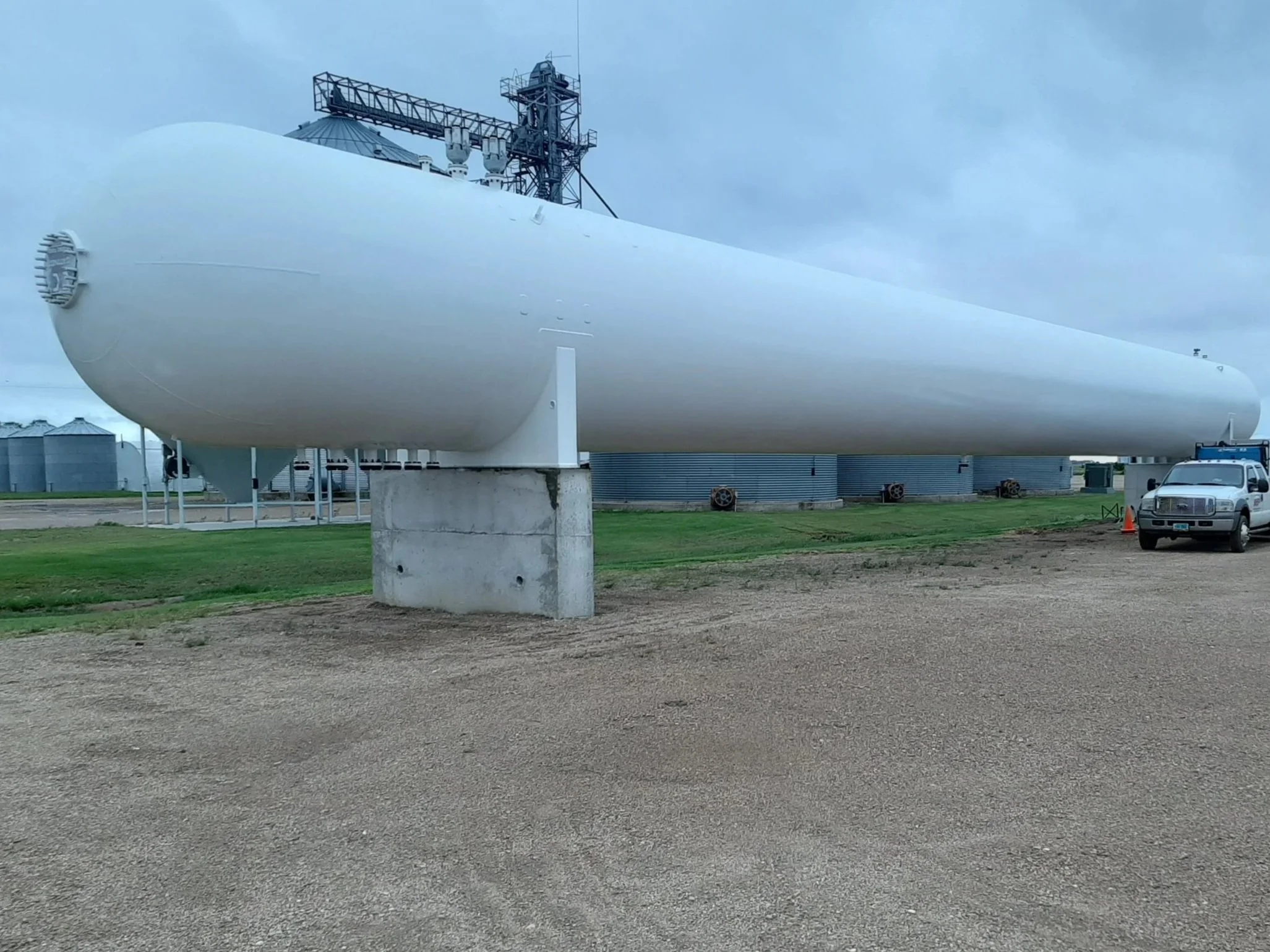 Large white industrial stationary bulk storage tank on concrete supports after structural repairs and maintenance in North Dakota.