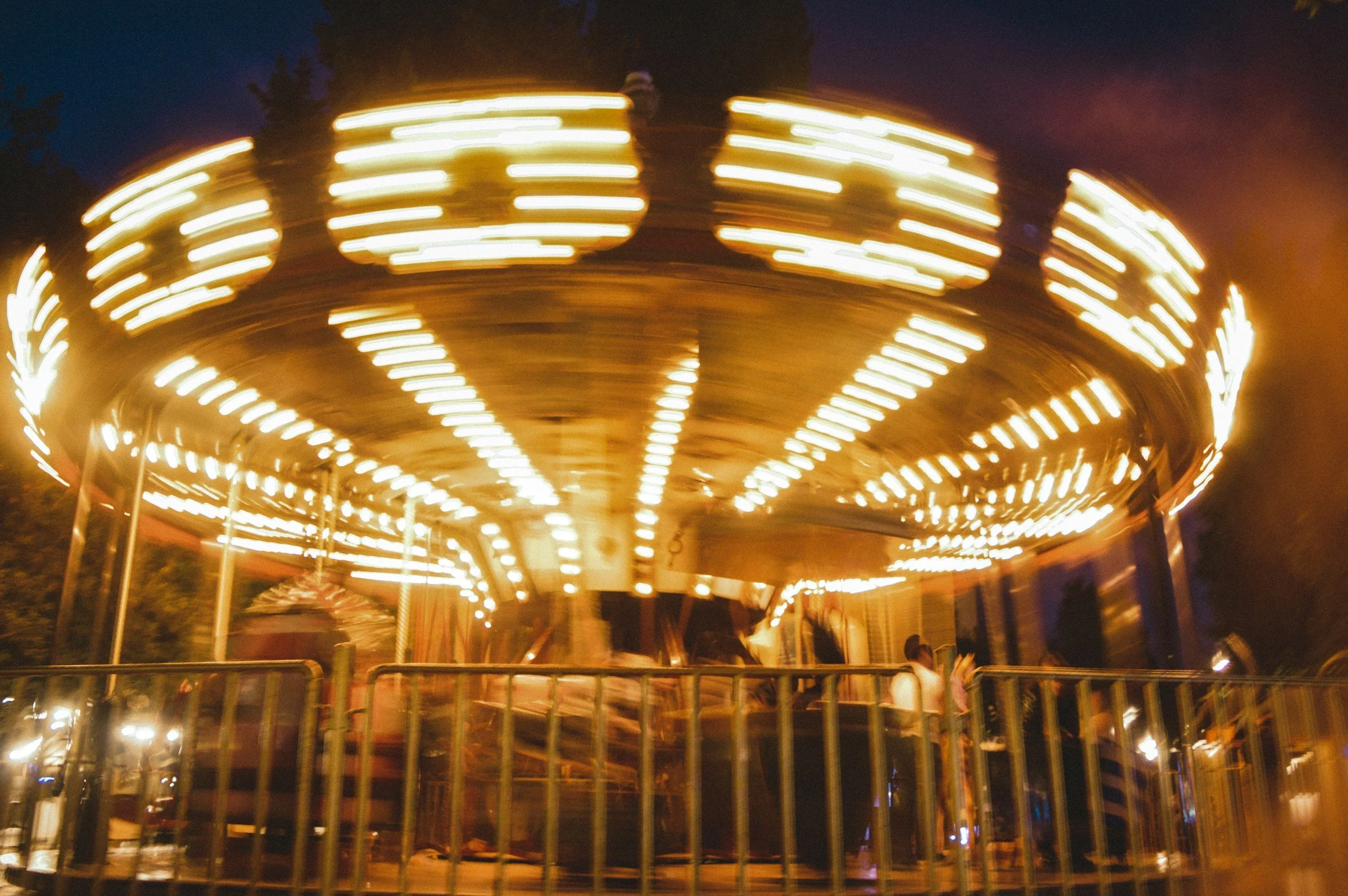 A carousel ride in motion with bright lights at night.