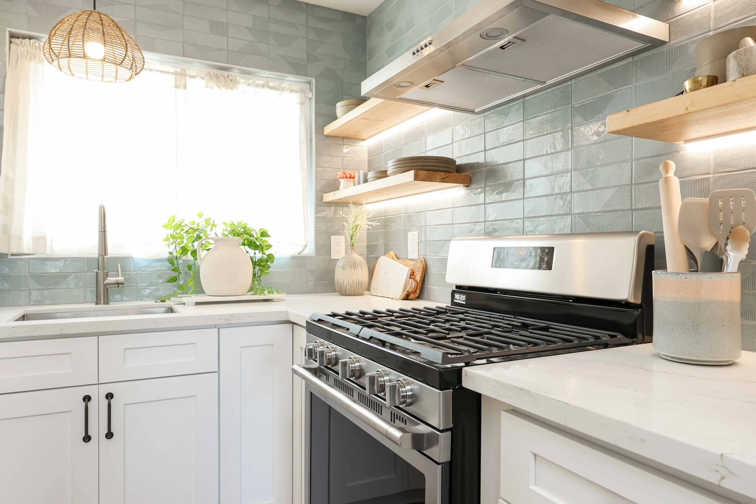 Kitchen with blue tile, open shelves and a gas range at Clementine B in Oceanside, designed by Salt and Sky Lodging Co.