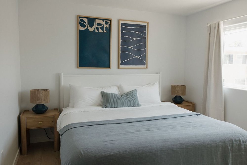 A bedroom in The East Cove with navy surf art and blue bedding