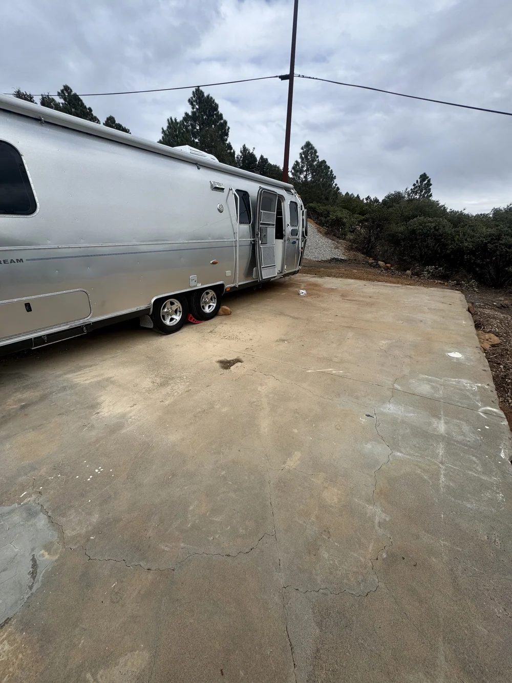 Before: the Airstream parked on a bare, cracked concrete pad at Restore Outpost, Wild Moon Ranch, Julian