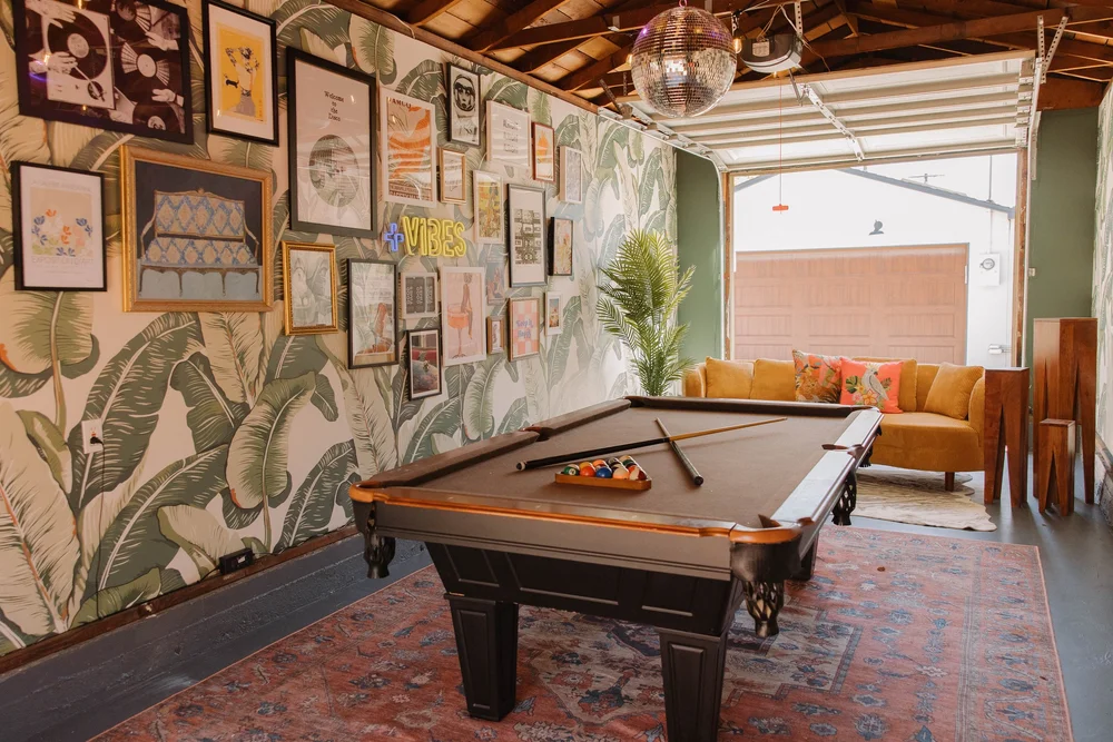The garage game room at Palm Parkside with a pool table and palm leaf wallpaper