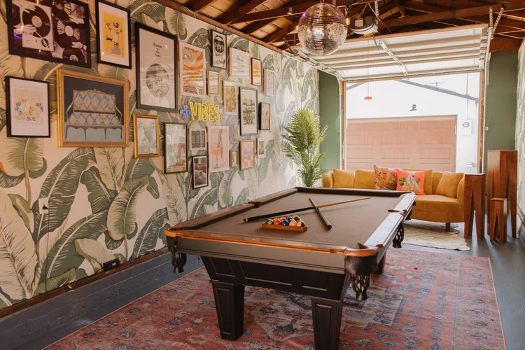 The garage game room at Palm Parkside with a pool table and palm leaf wallpaper