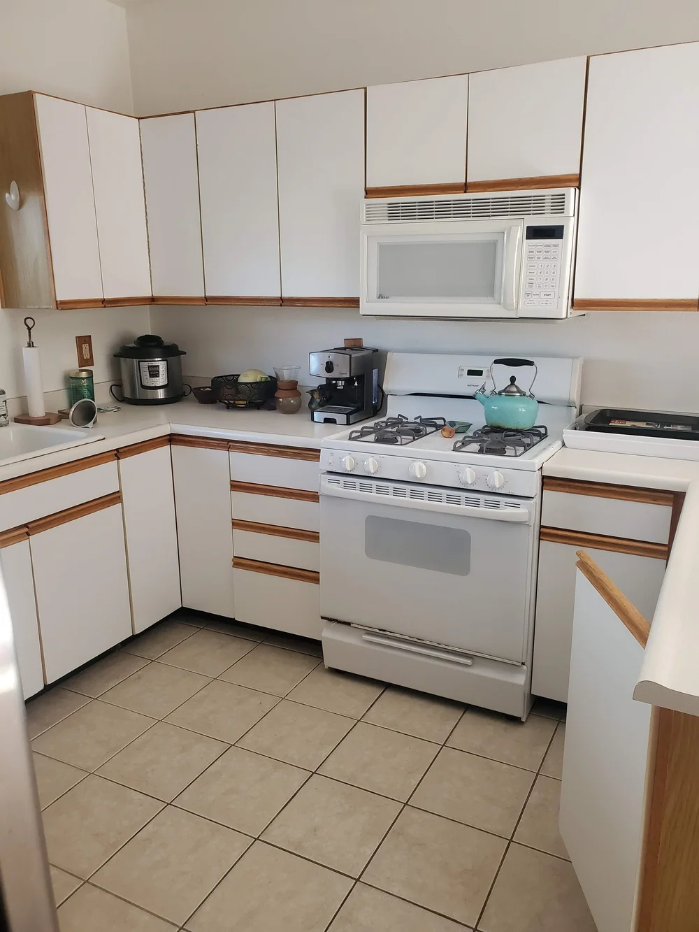 Before: Kitchen with white cabinets and a tile floor at OB Surfer's Paradise in Ocean Beach