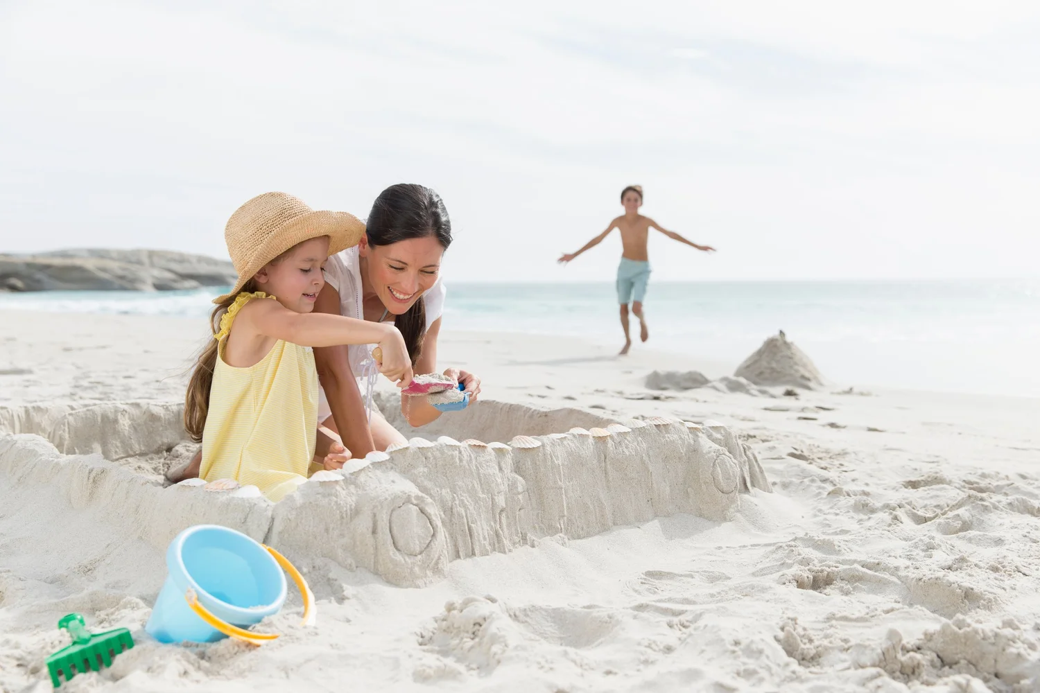 A mother and two children building a sandcastle on the beach