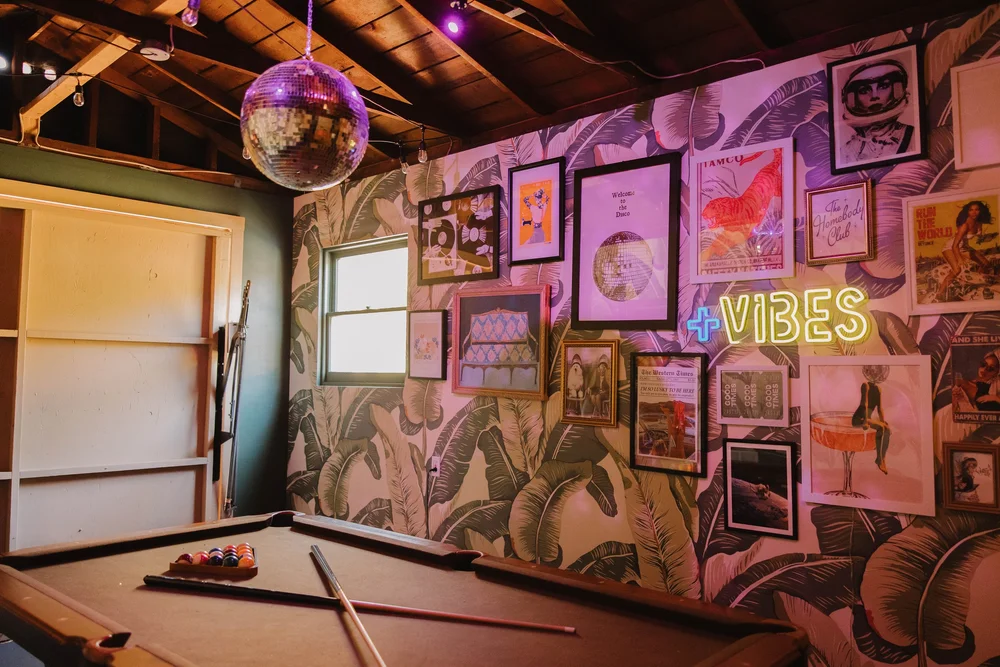 The pool table and a wall of framed art in the garage game room at Palm Parkside