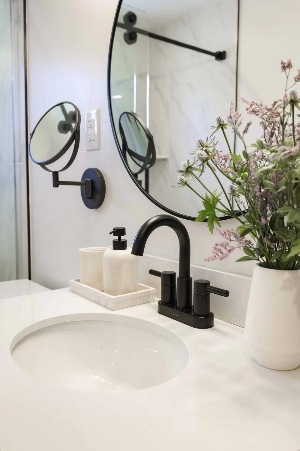 The vanity with a black faucet and a round mirror in Unit Two at The Swell, Oceanside