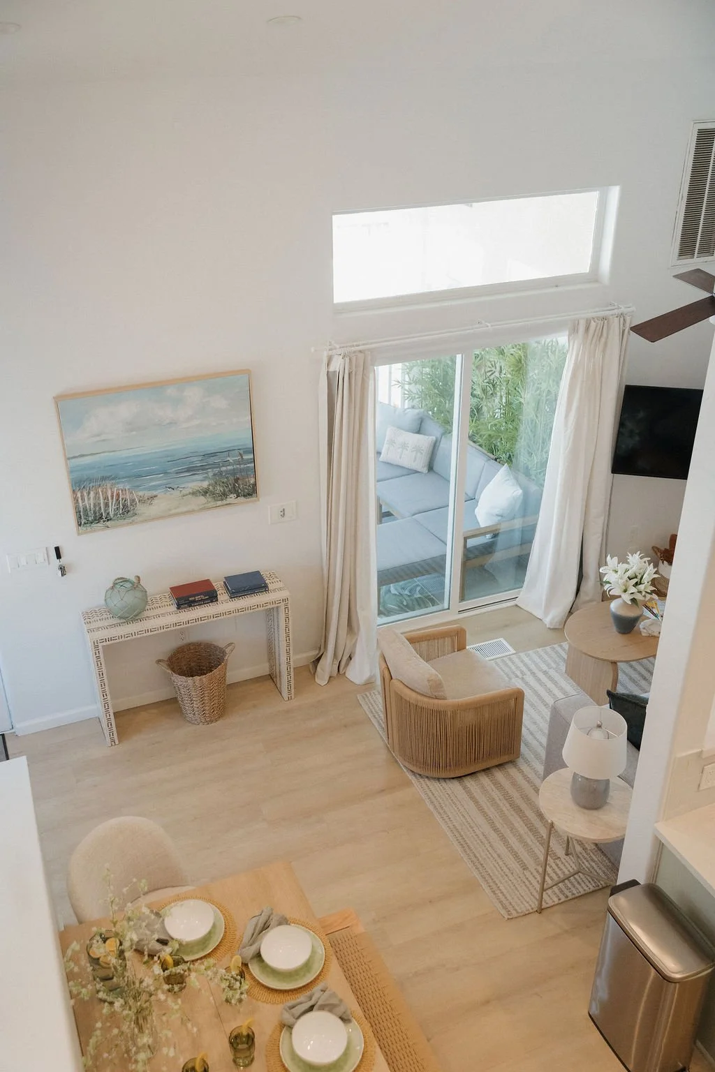 The West Cove living and dining room with beach art and a balcony door