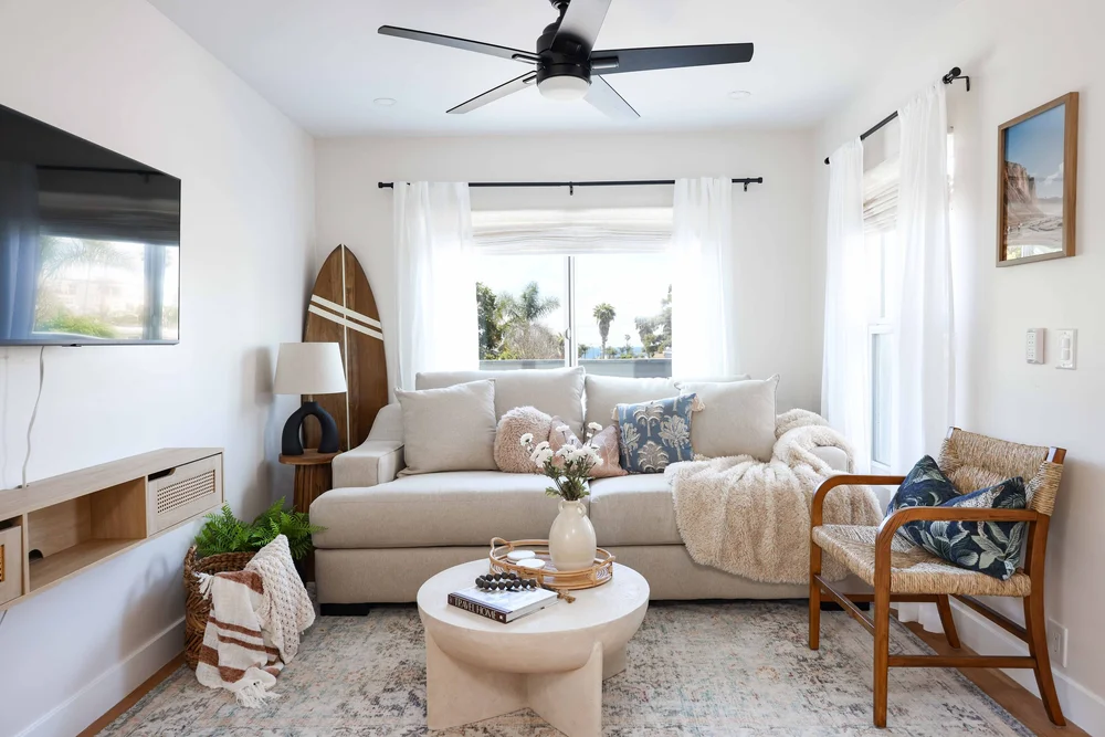 The living room with a cream sofa, a surfboard and a round coffee table in Unit Two at The Swell, Oceanside
