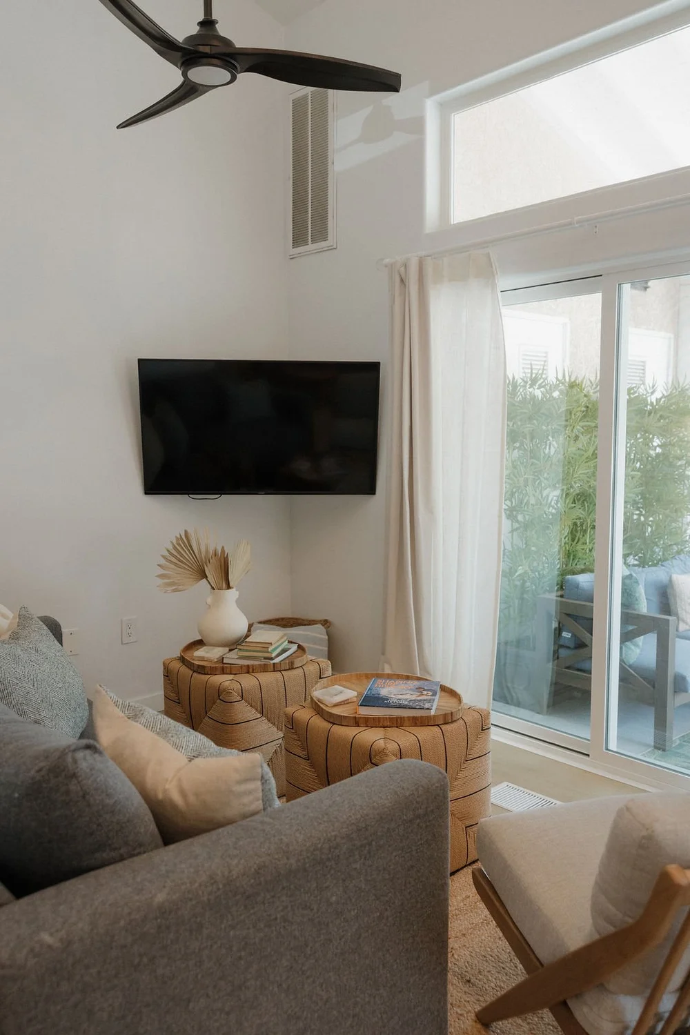 Woven stools and a sliding door to the balcony in The East Cove living room