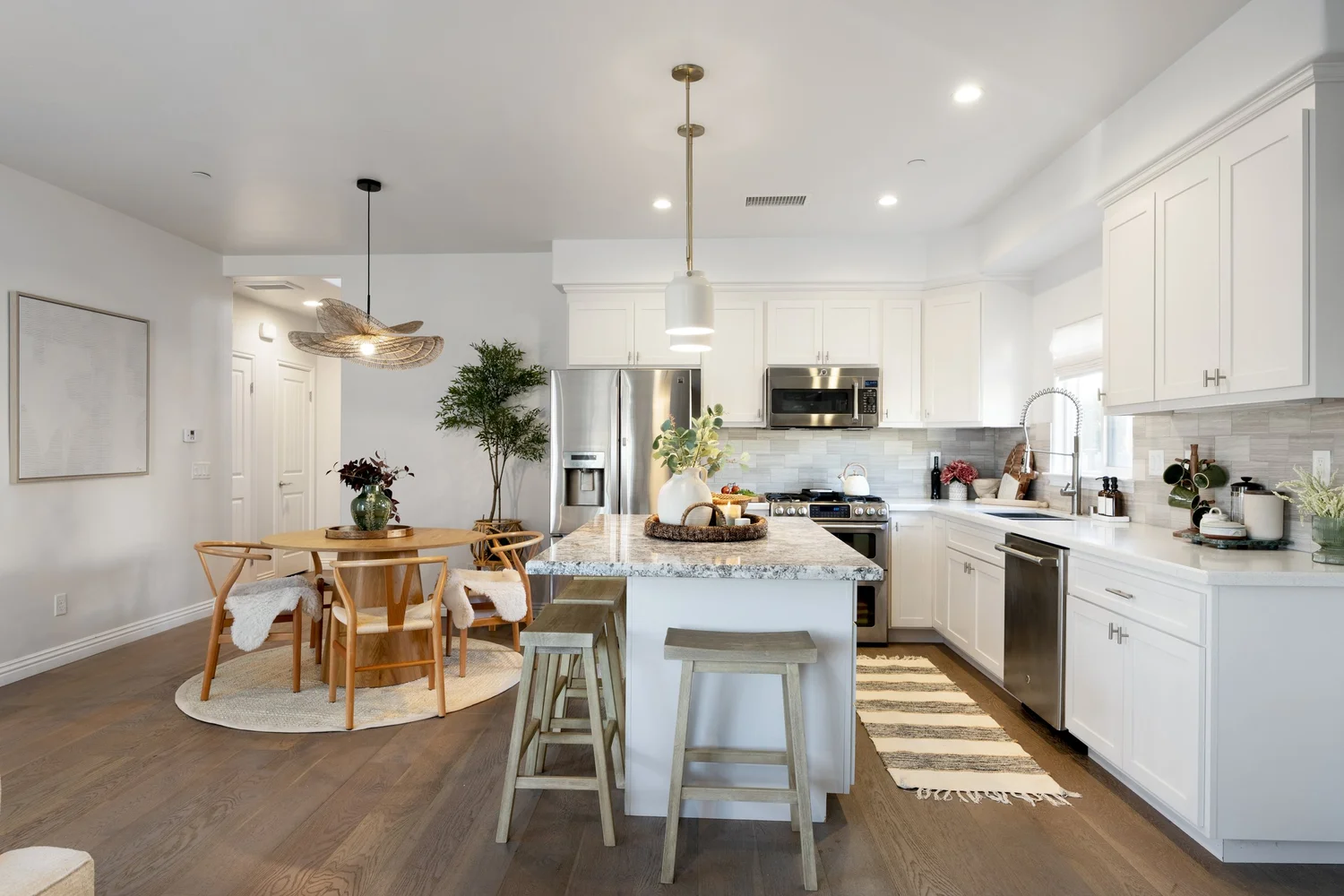 The white kitchen with an island, bar stools and a round dining table at The Coastal Palm in Pacific Beach