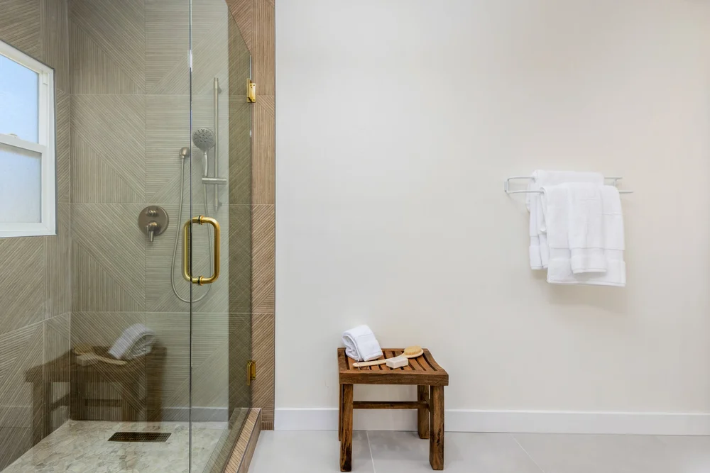 The glass shower and a teak stool with towels in Unit Three at The Swell, Oceanside