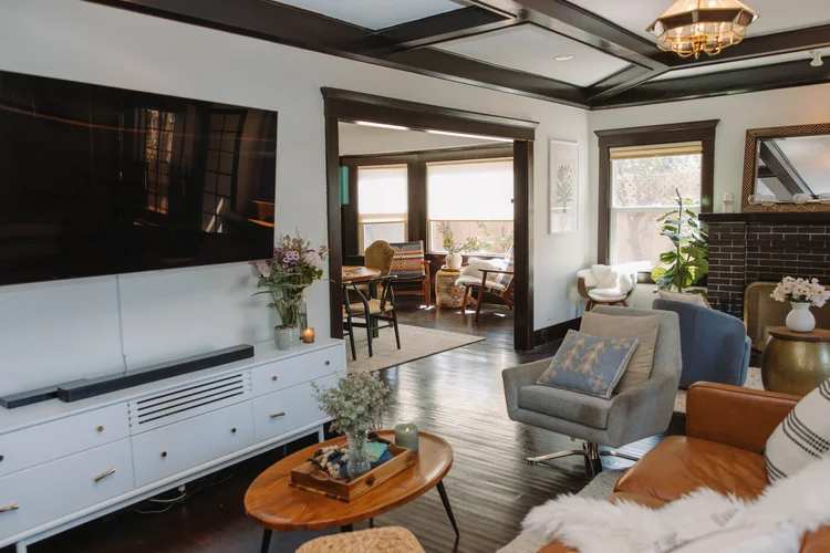 The living room at Palm Parkside with coffered ceilings, original dark wood trim and a wall of windows