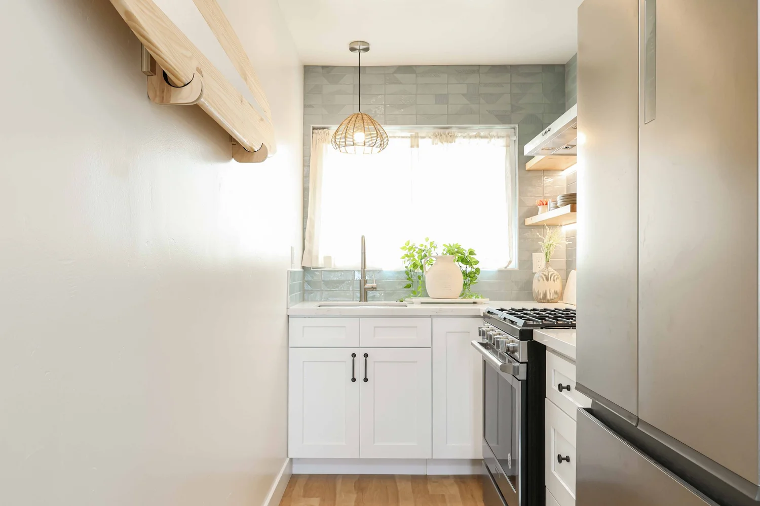 Galley kitchen with white cabinets and a blue tile backsplash at Clementine B in Oceanside, designed by Salt and Sky Lodging Co.