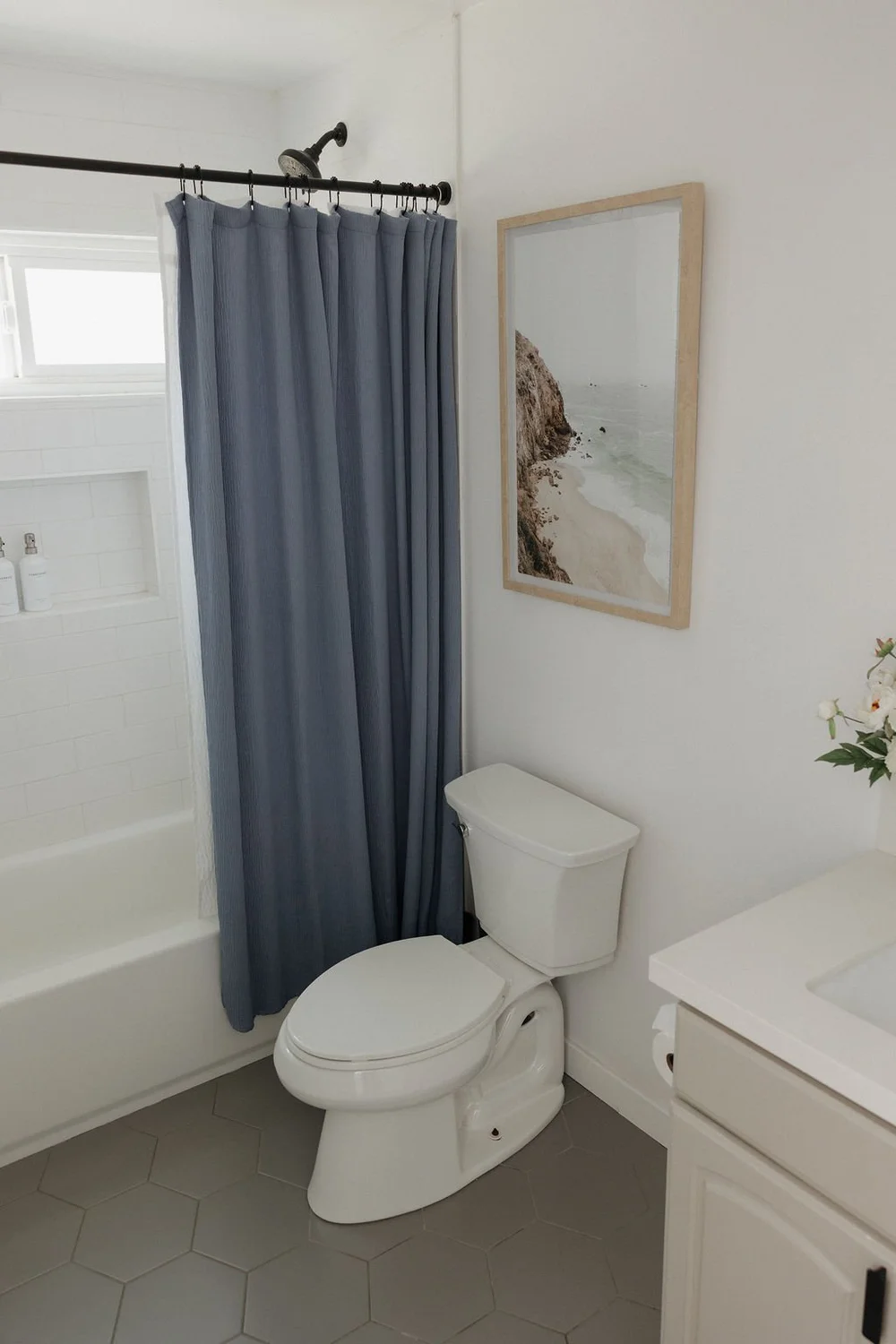 A bathroom in The East Cove with a blue shower curtain and beach art