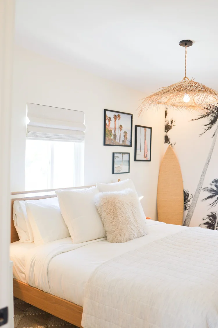 The bedroom with a palm mural, a woven pendant and a surfboard in Unit Three at The Swell, Oceanside