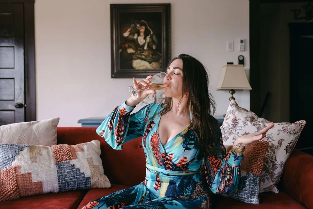 A guest relaxing with a glass of wine on the red sofa in the master suite living room at Palm Parkside
