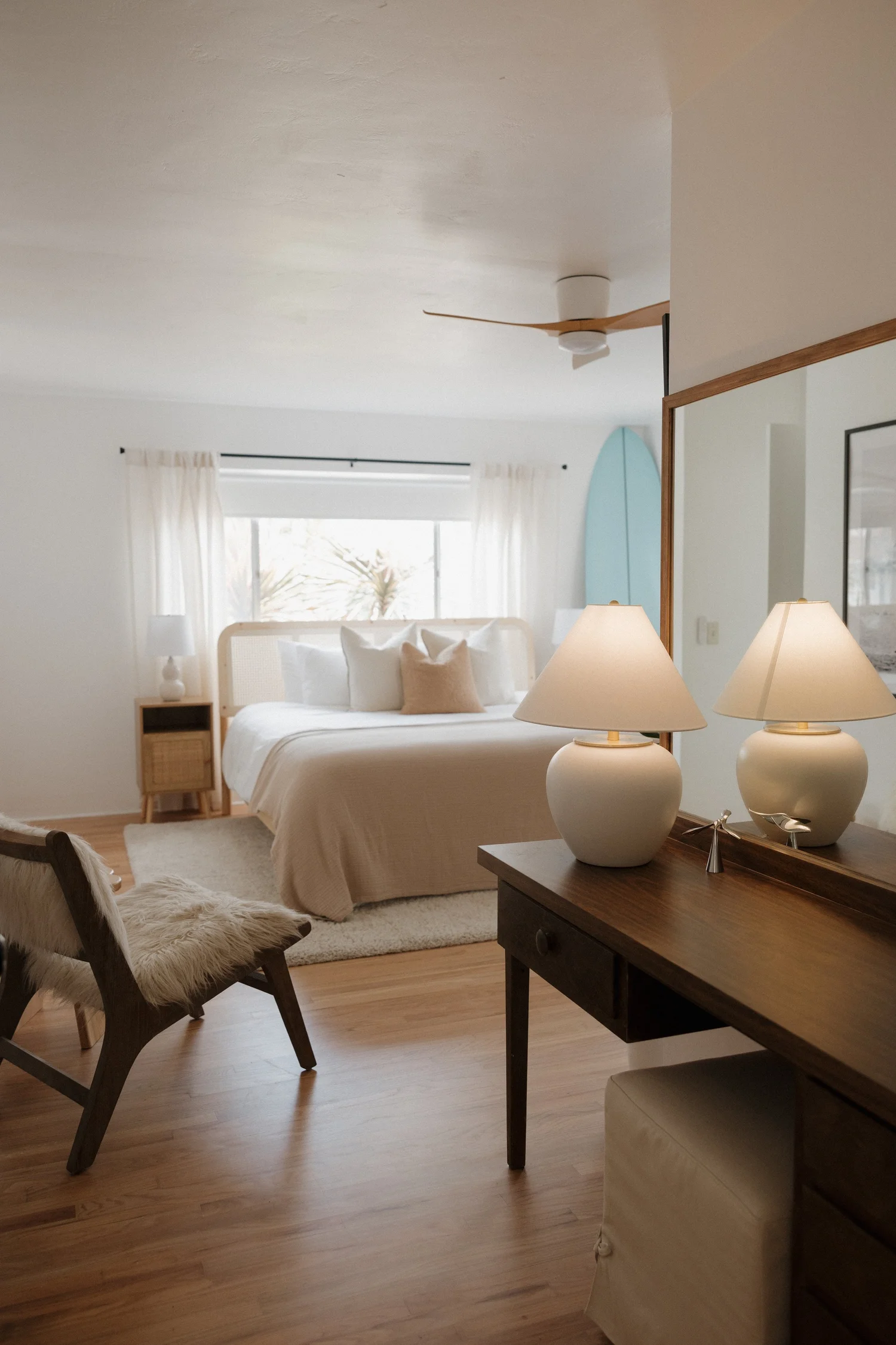 The primary bedroom at Wavehouse with a woven headboard, twin lamps and a vanity