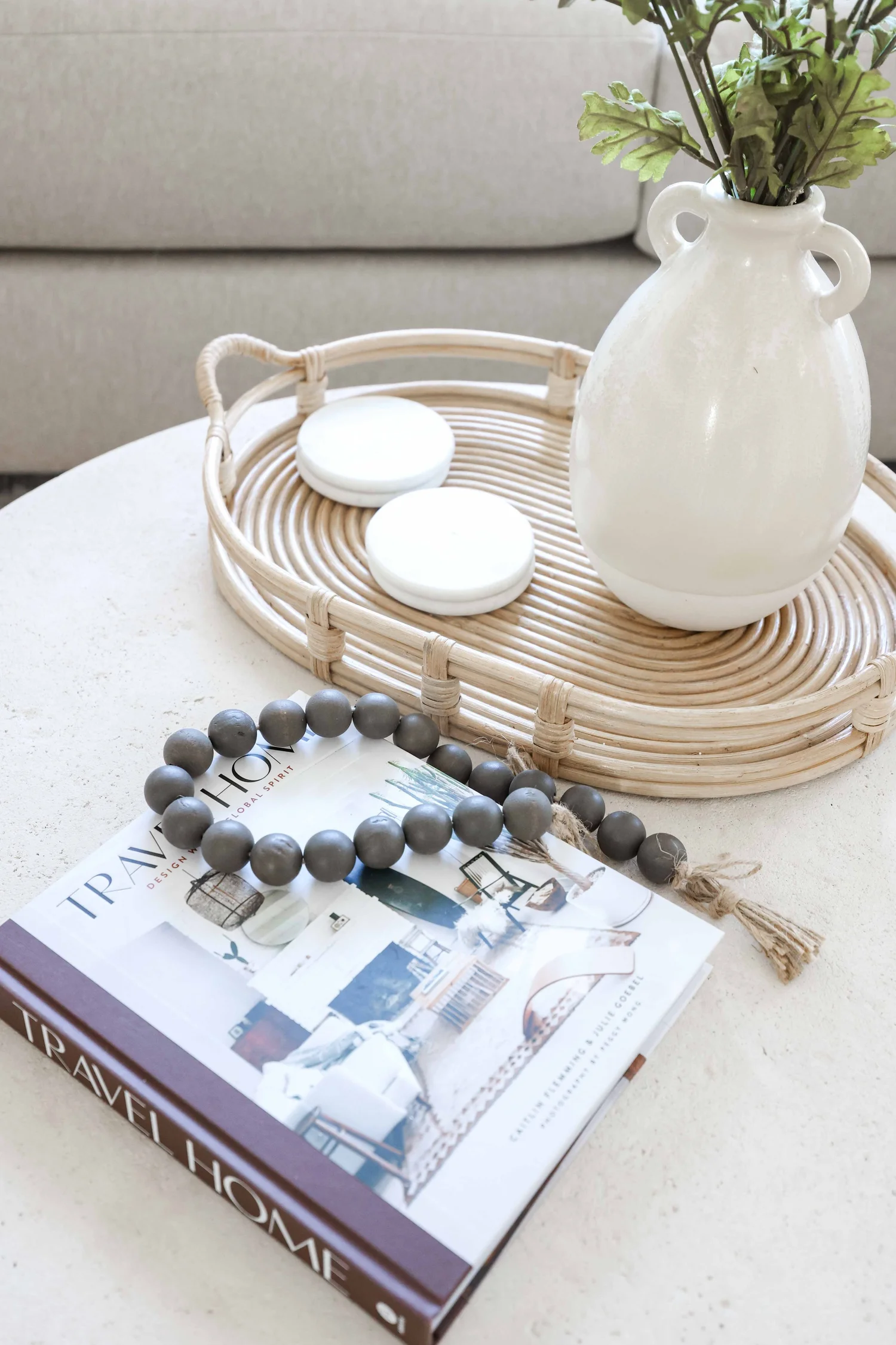Coffee table styling with a rattan tray, beads and a vase at Clementine A in Oceanside, designed by Salt and Sky Lodging Co.