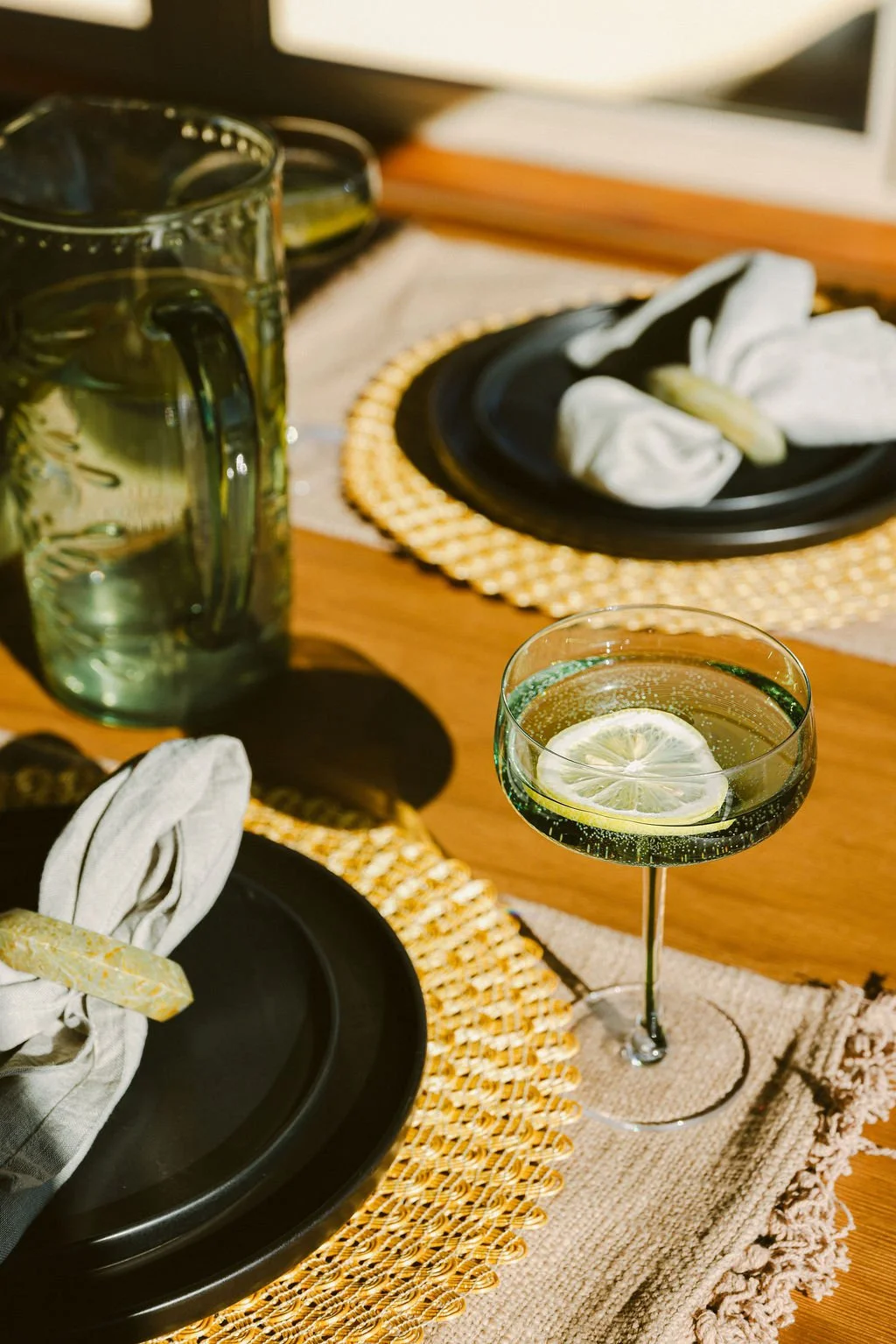 Table set with black plates, woven chargers and cocktails