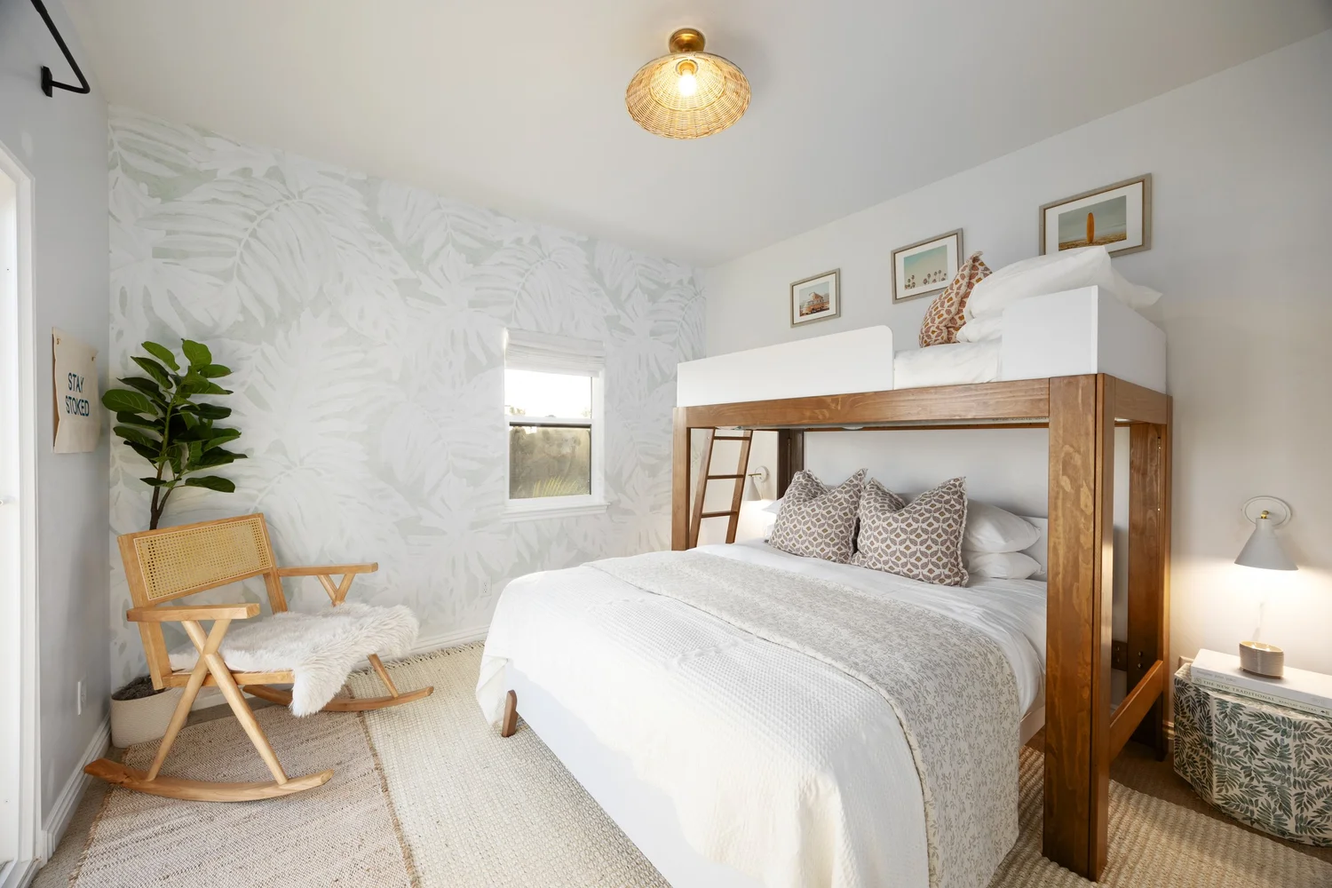 Bedroom with a wood bunk loft, a white bed and a rocking chair at Coastal Palm in Pacific Beach, designed by Salt and Sky Lodging Co.
