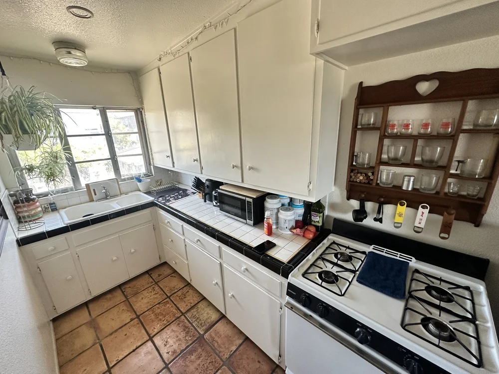 Before: Kitchen with white cabinets and a tile floor at Clementine C in Oceanside