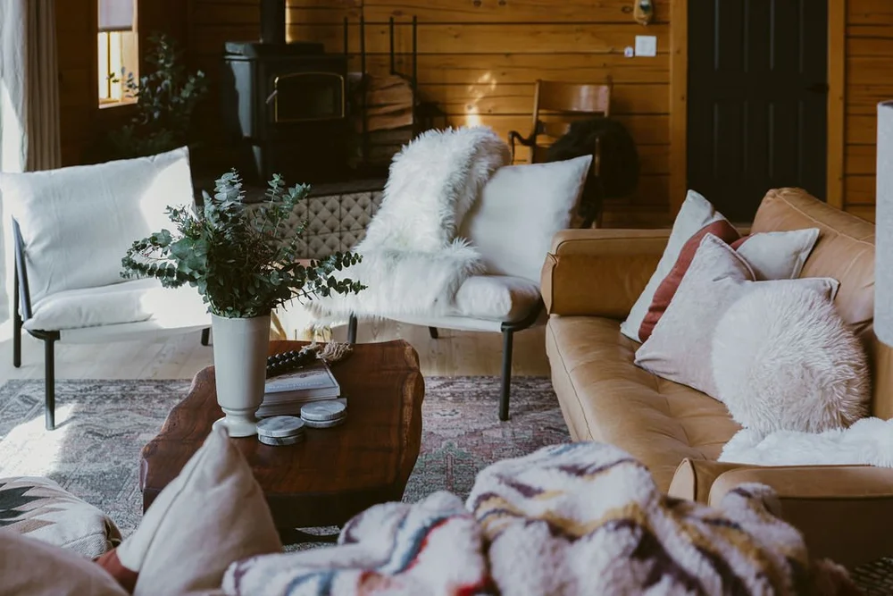 Cozy great room with a leather sofa, wood-burning stove, and eucalyptus at Dark Moon Chalet, Julian CA