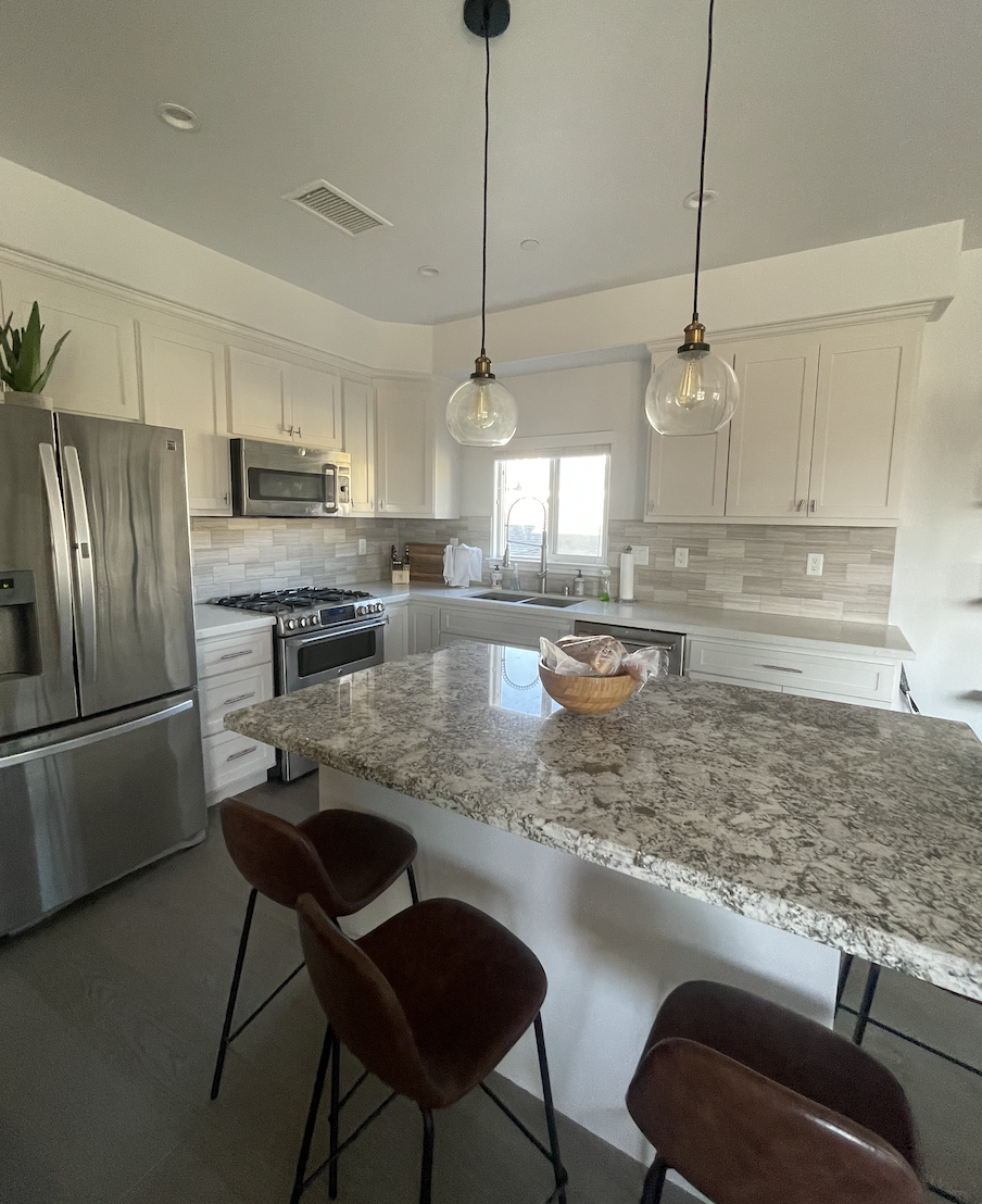 Before: Kitchen with a granite island and leather stools at Coastal Palm in Pacific Beach