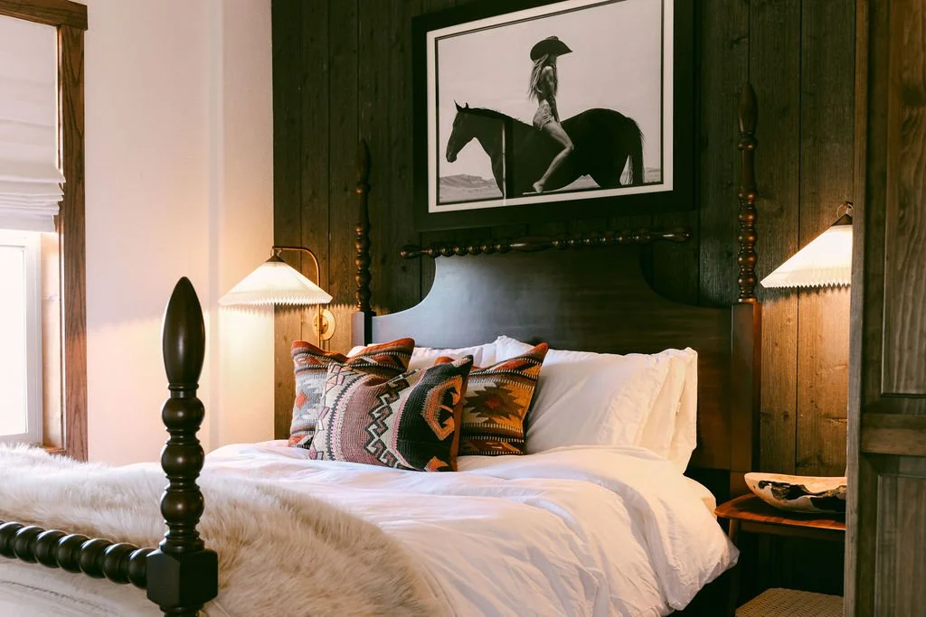 A dark wood bedroom at Wild Moon Ranch near Julian, with a turned post bed, patterned pillows and a western print