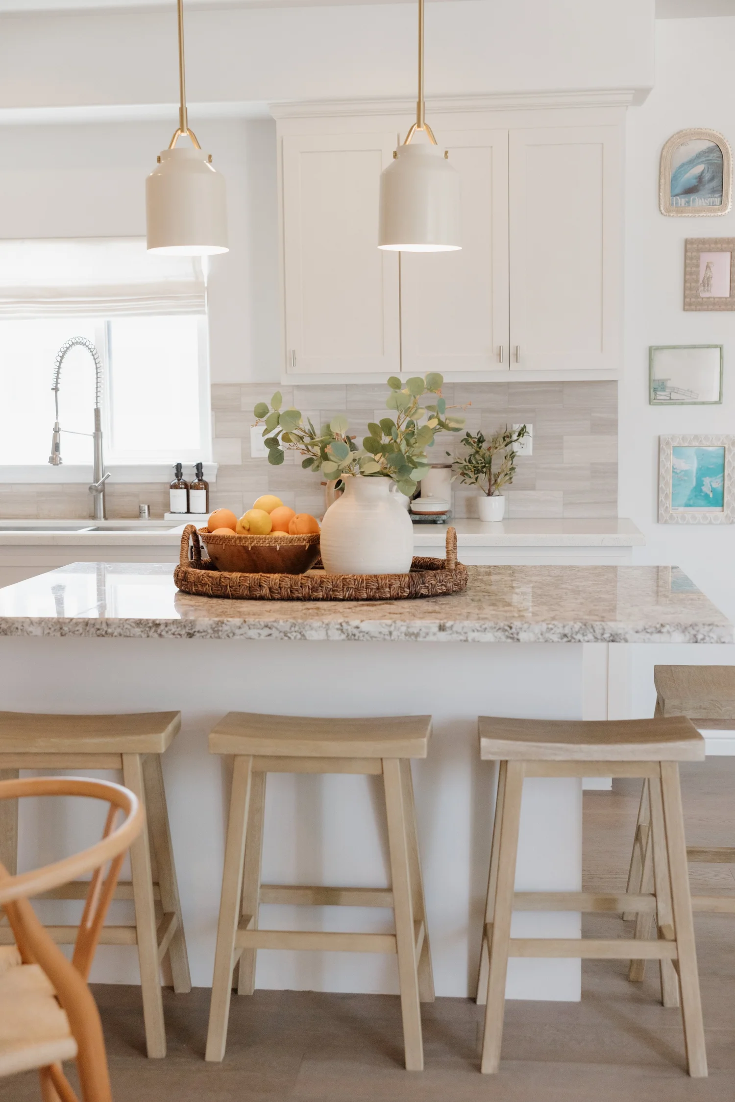 Kitchen island with stools, pendant lights and a granite counter at Coastal Palm in Pacific Beach, designed by Salt and Sky Lodging Co.