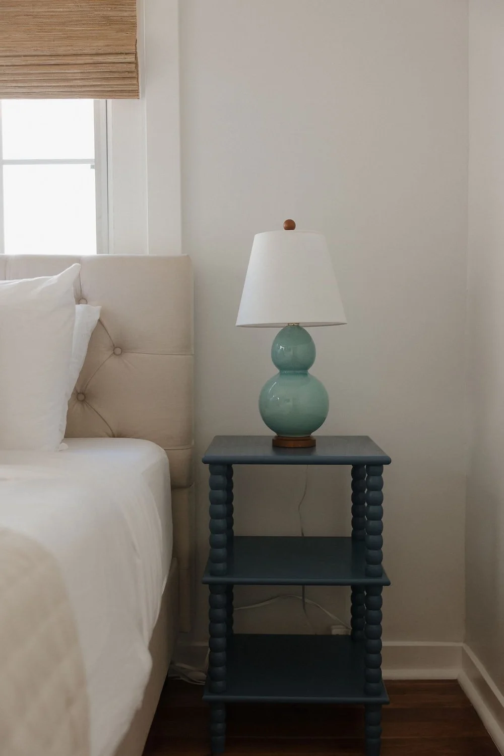 A blue nightstand and a seafoam lamp beside the bed in a bedroom at The Villa