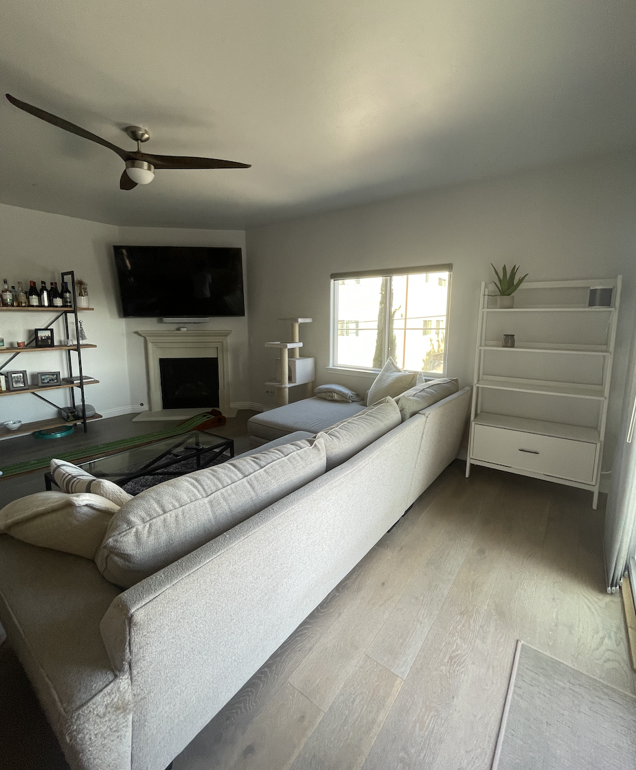 Before: Living room with a sectional and fireplace at Coastal Palm in Pacific Beach