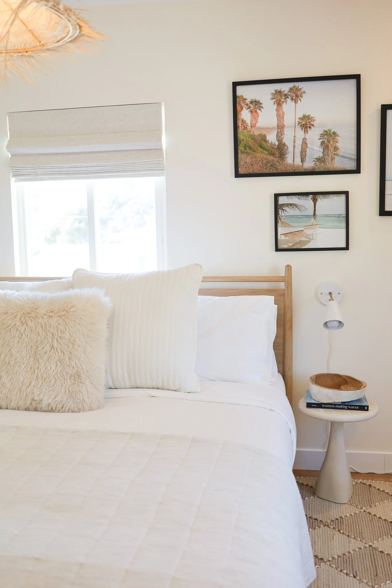 Bedroom with white bedding, sheepskin pillows and palm photos at Clementine C in Oceanside, designed by Salt and Sky Lodging Co.
