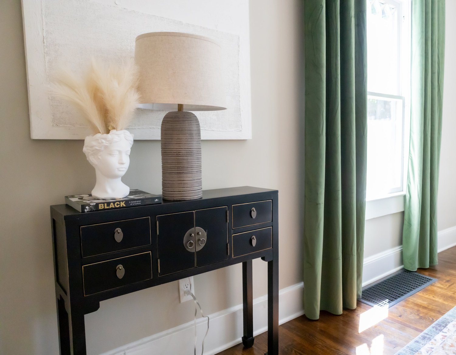 Black console table with a sculptural lamp and green velvet curtains at Elmsgate in Birmingham, designed by Salt and Sky Lodging Co.