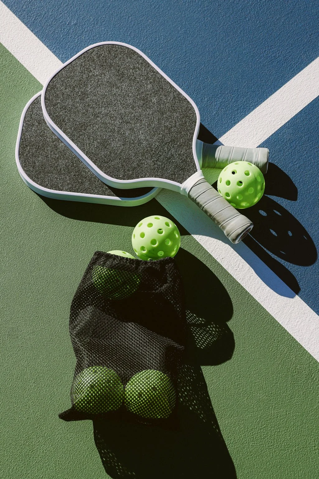 Pickleball paddles and balls on the court at Wild Moon Ranch