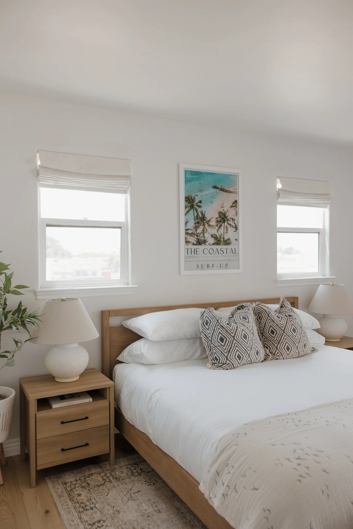 Bedroom with a wood bed, patterned pillows and a vintage surf poster at Coastal Palm in Pacific Beach, designed by Salt and Sky Lodging Co.