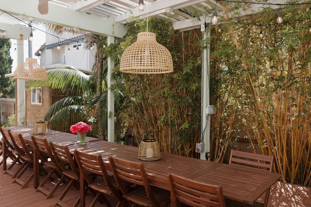 The long courtyard dining table at Seaside Square under woven pendant lights