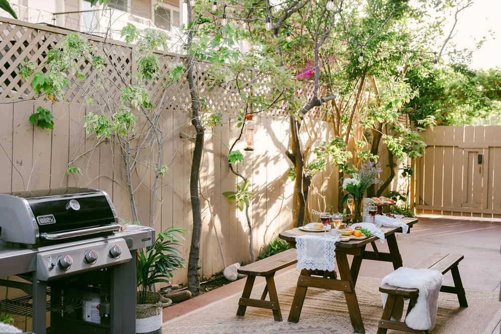 The propane grill and a picnic table under the trees at Palm Parkside