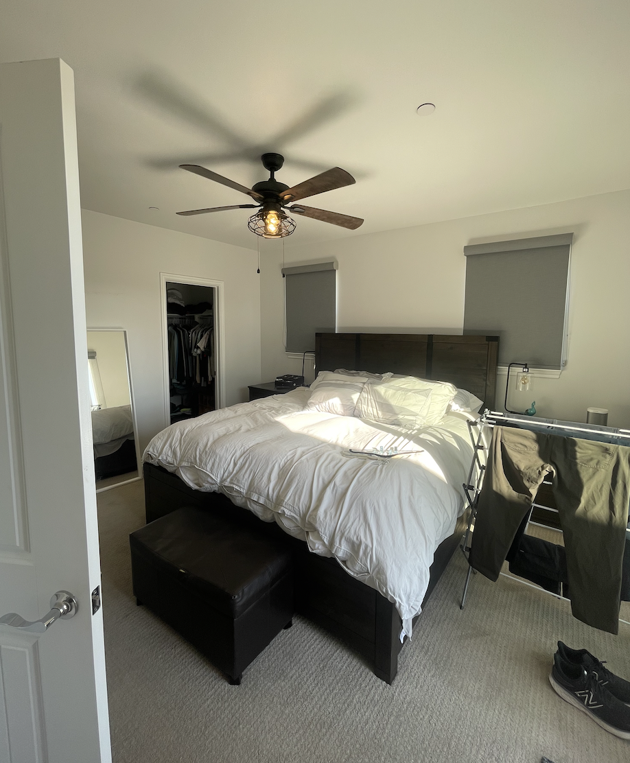 Before: Bedroom with a dark bed and bare walls at Coastal Palm in Pacific Beach
