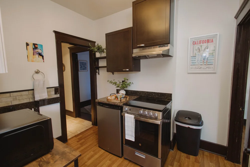 The second kitchen on the first floor at Palm Parkside, next to the main kitchen, with a stove, dishwasher and dark wood cabinets