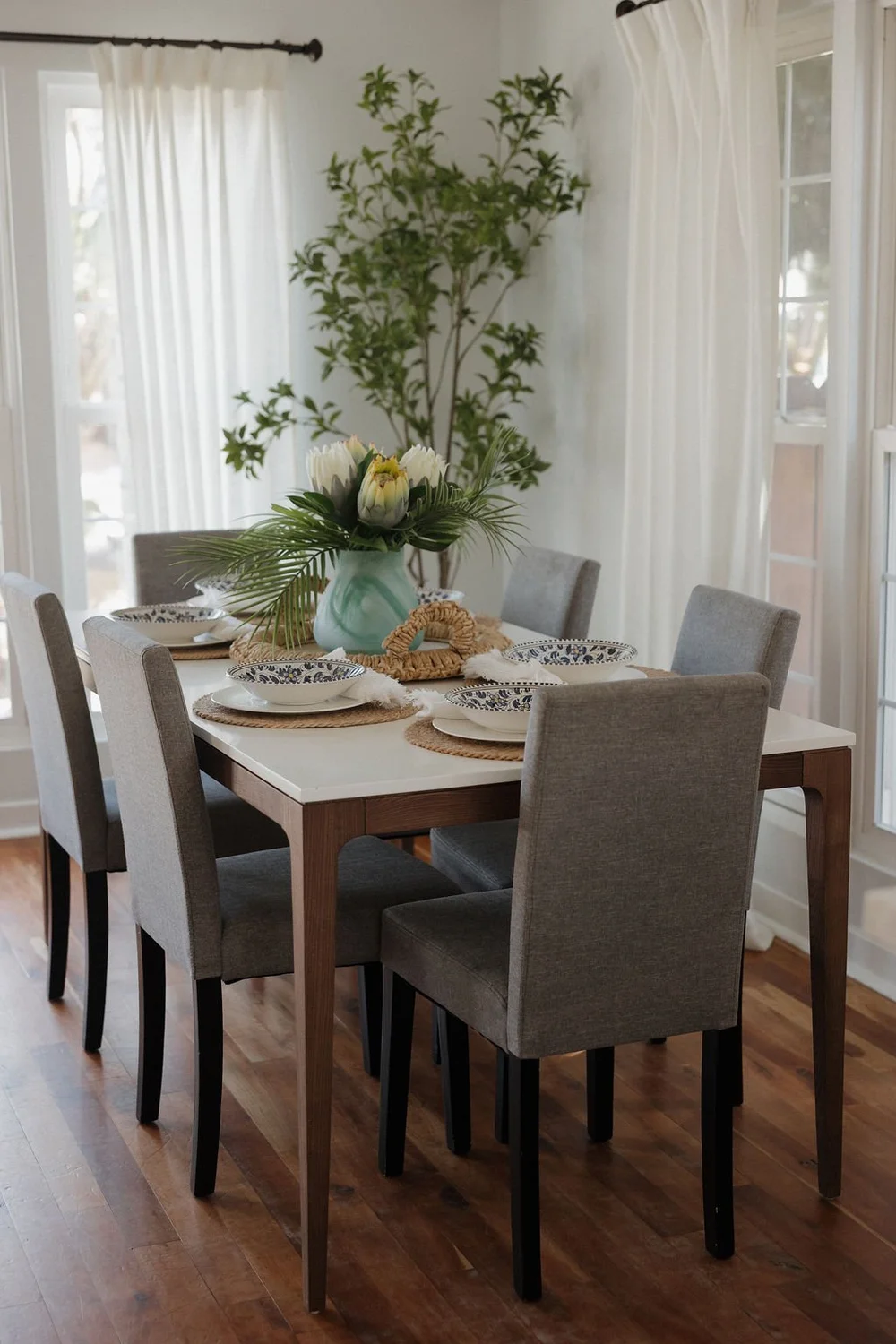The dining table for six in The Villa with gray chairs and tall windows