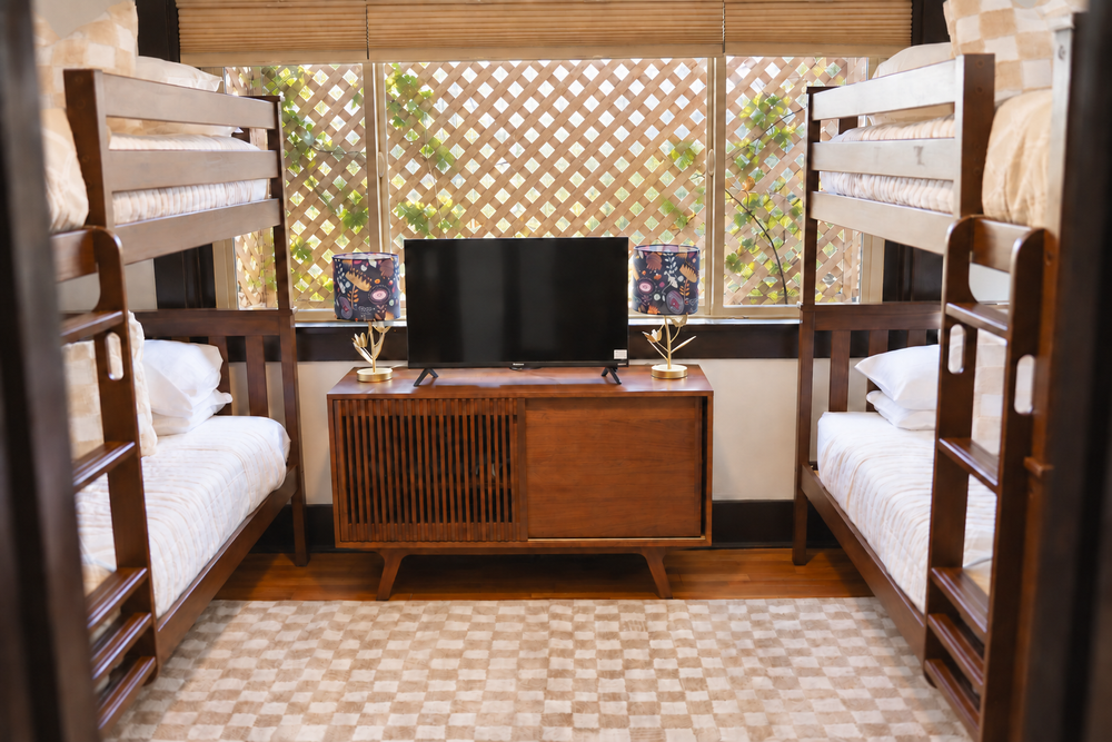 The first floor bunk room at Palm Parkside with two sets of wood bunk beds, a TV and a checkered rug