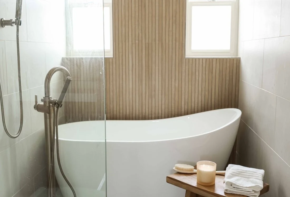 The bathroom at The Swell Unit One in Oceanside, with a freestanding soaking tub against a slatted wood wall