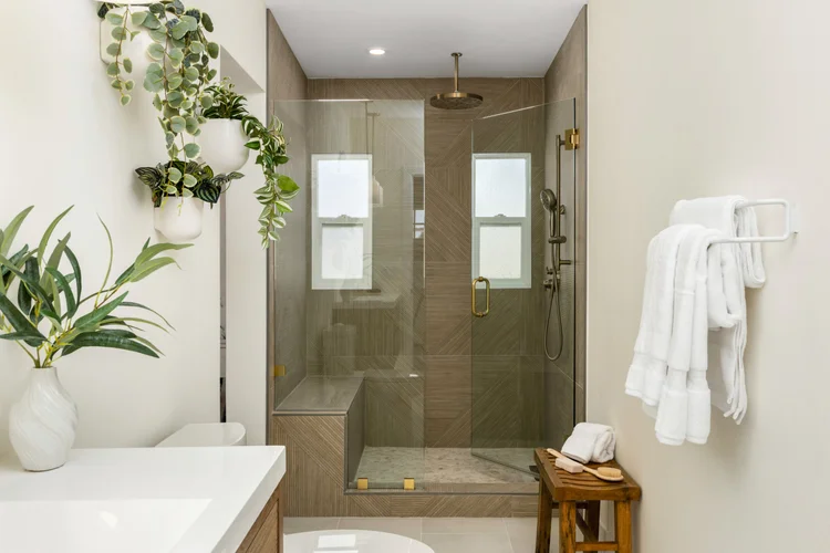 The spa bathroom with a walk-in glass shower, rain showerhead and teak stool in Unit Three at The Swell, Oceanside