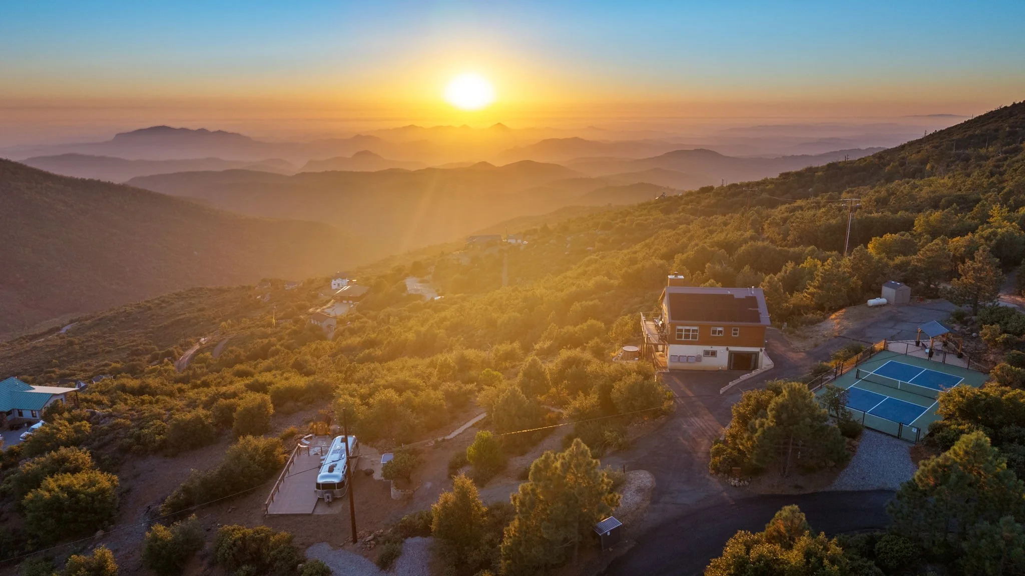 Sunset over Wild Moon Ranch with the private pickleball court, cabin and Restore Outpost Airstream, a retreat venue near Julian and San Diego